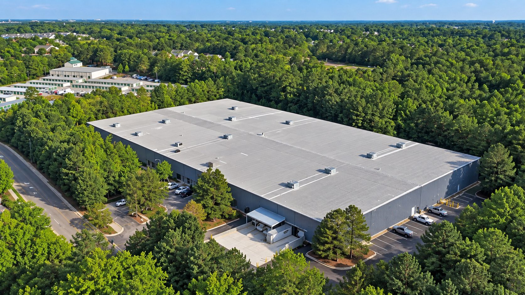 Aerial view of 1711 Corporation Parkway in Raleigh, a large industrial building set among dense pine forest