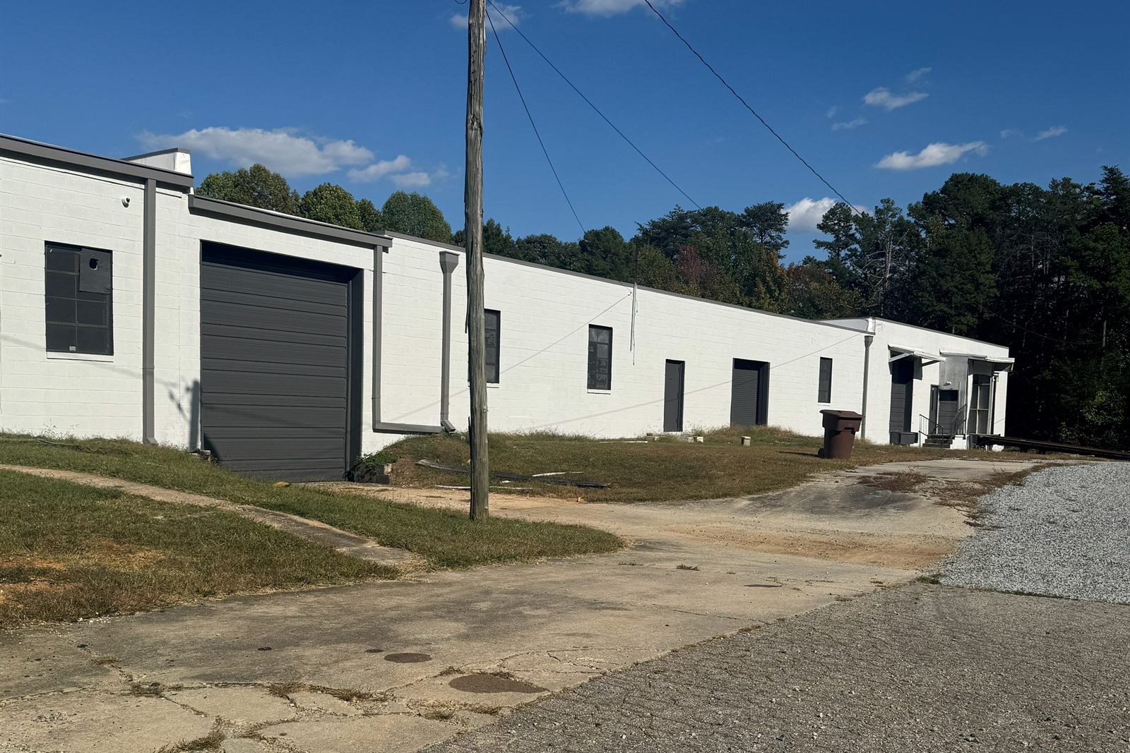 A paved drive leading up to an oversized dark gray drive-in door at 314 Mandustry Street, with more doors along the white masonry building beyond