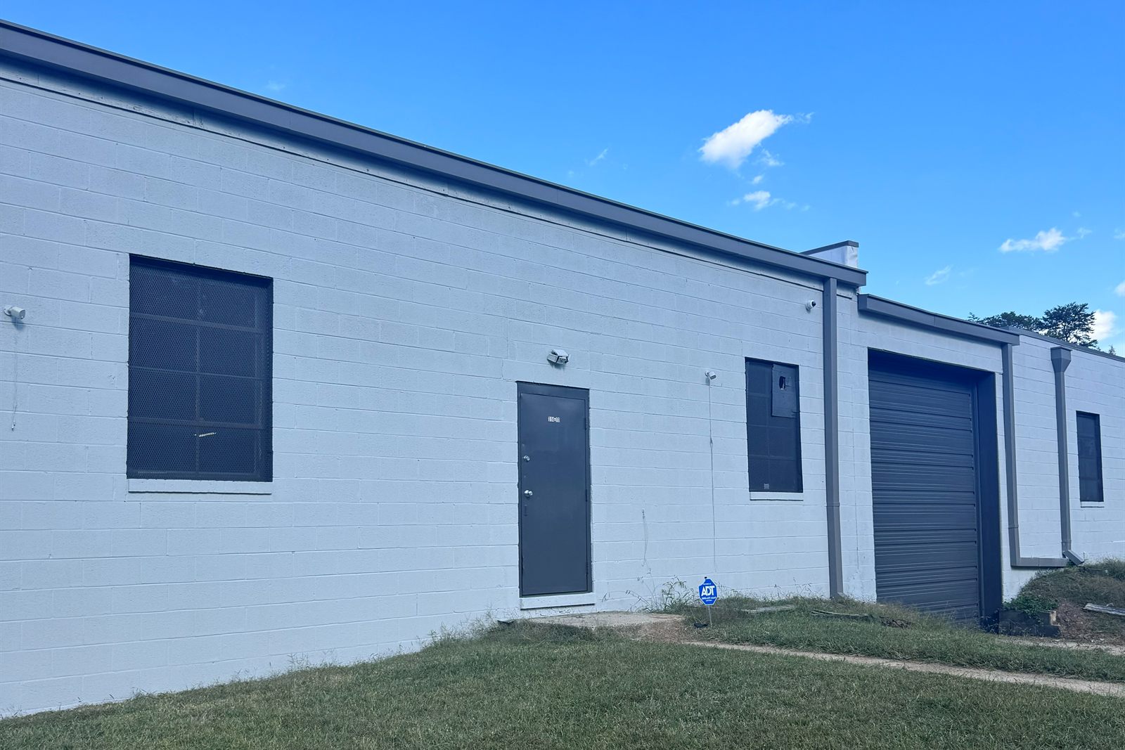 Close view of a suite entry at 314 Mandustry Street: white painted block wall, dark gray steel door, window, and a drive-in door under gray trim