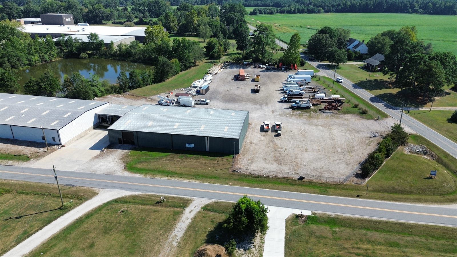 Aerial view of the fenced gravel outdoor storage yard at 4734 Potato House Court, with trucks and equipment parked beside the warehouse buildings
